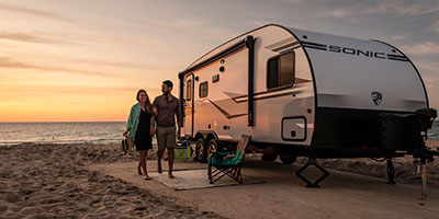 2020 Venture RV Sonic SN210VTB Travel Trailer with couple at beach campsite