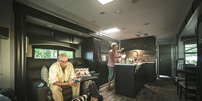 2020 Venture RV SportTrek Touring Edition STT343VIK Travel Trailer with man and woman in living room and kitchen