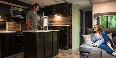 2019 Venture RV SportTrek ST327VIK Travel Trailer with couple in kitchen area